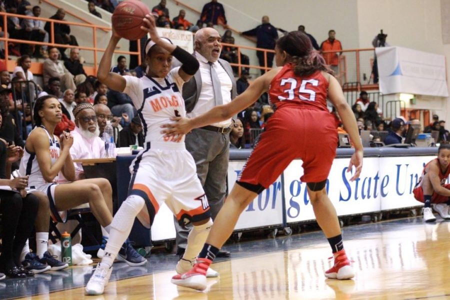 Breannan Farrar attempts to make a move with the ball as former head coach Donald Beasley gives orders in the background.
Photo by Terry Wright.