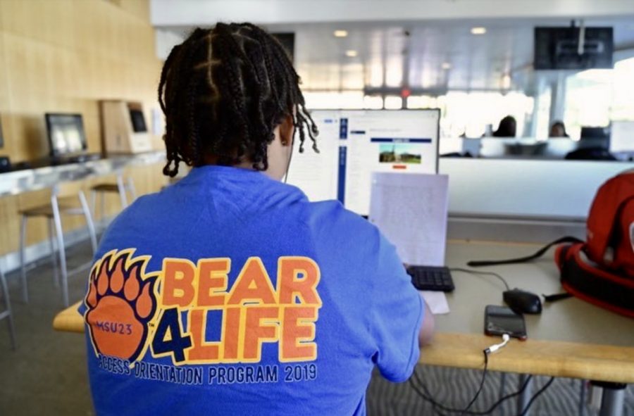 A+Morgan+student+utilizes+an+Earl+S.+Richardson+Library+computer+while+wearing+a+2019+ACESS+Orientation+Program+shirt.