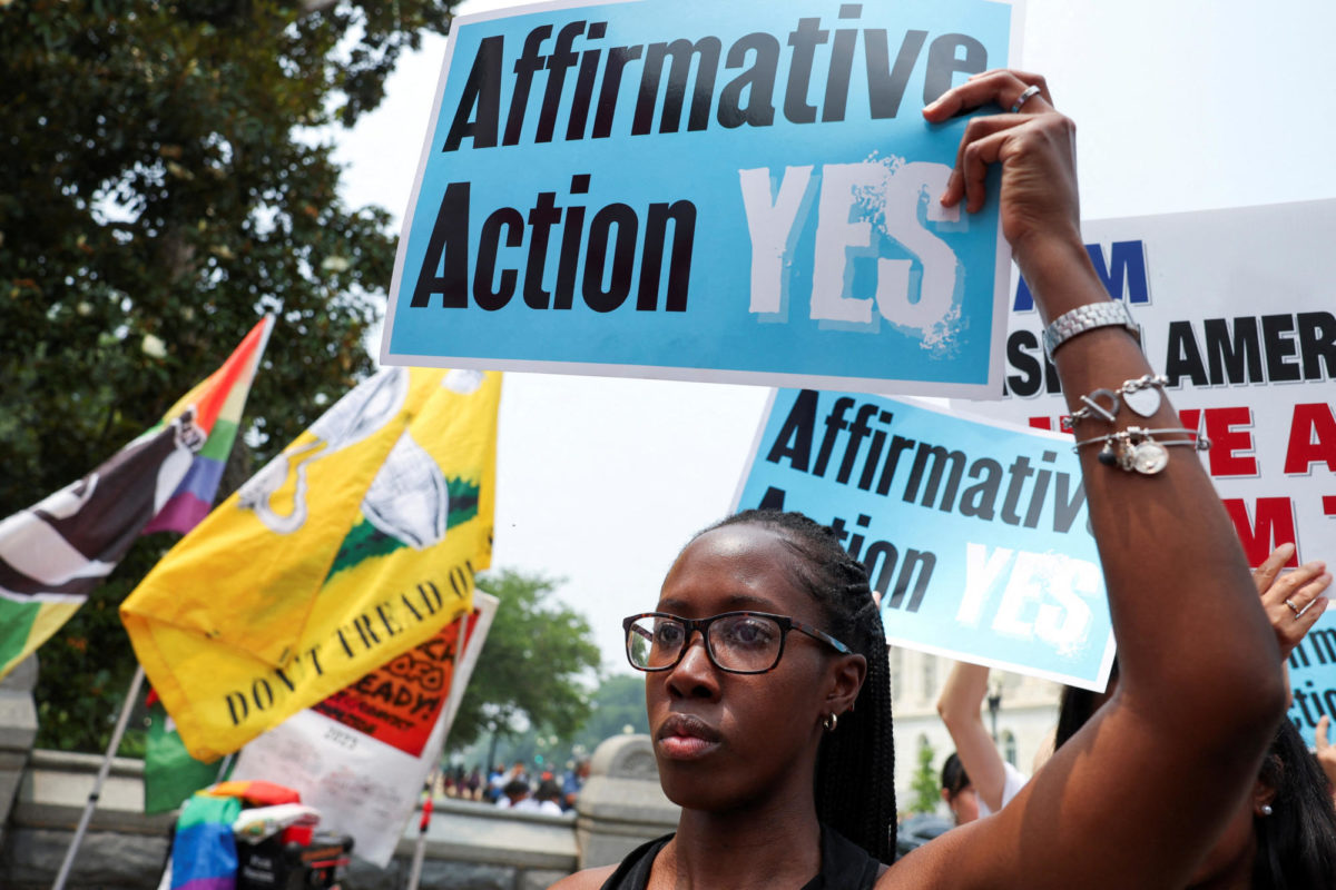 A woman holds a sign as demonstrators for and against the U.S. Supreme Court decision to strike down race-conscious student admissions programs at Harvard University and the University of North Carolina confront each other, in Washington, U.S., June 29, 2023. REUTERS/Evelyn Hockstein/File Photo