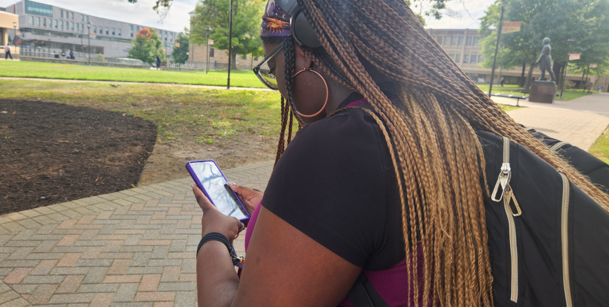 A Morgan student scrolls through an app while sitting in the university's quad. (MSU Spokesman photo by Lillian Stephens