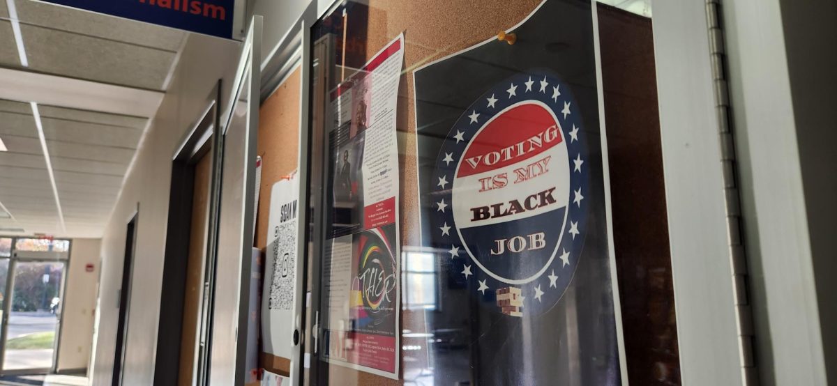 A sign reads "voting is my Black job." The sign hangs in on a community Board at Morgan State University,