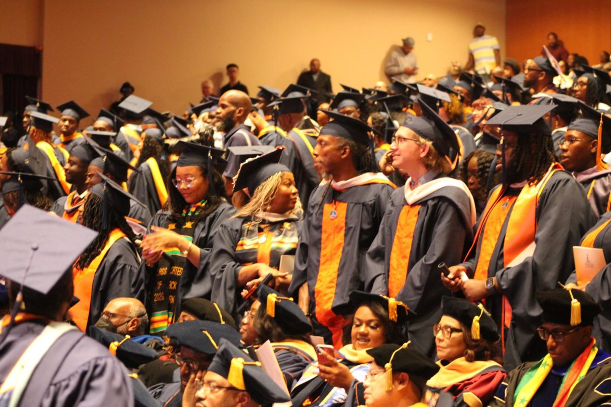 Graduates look on as their peers walk the stage and receive their degrees